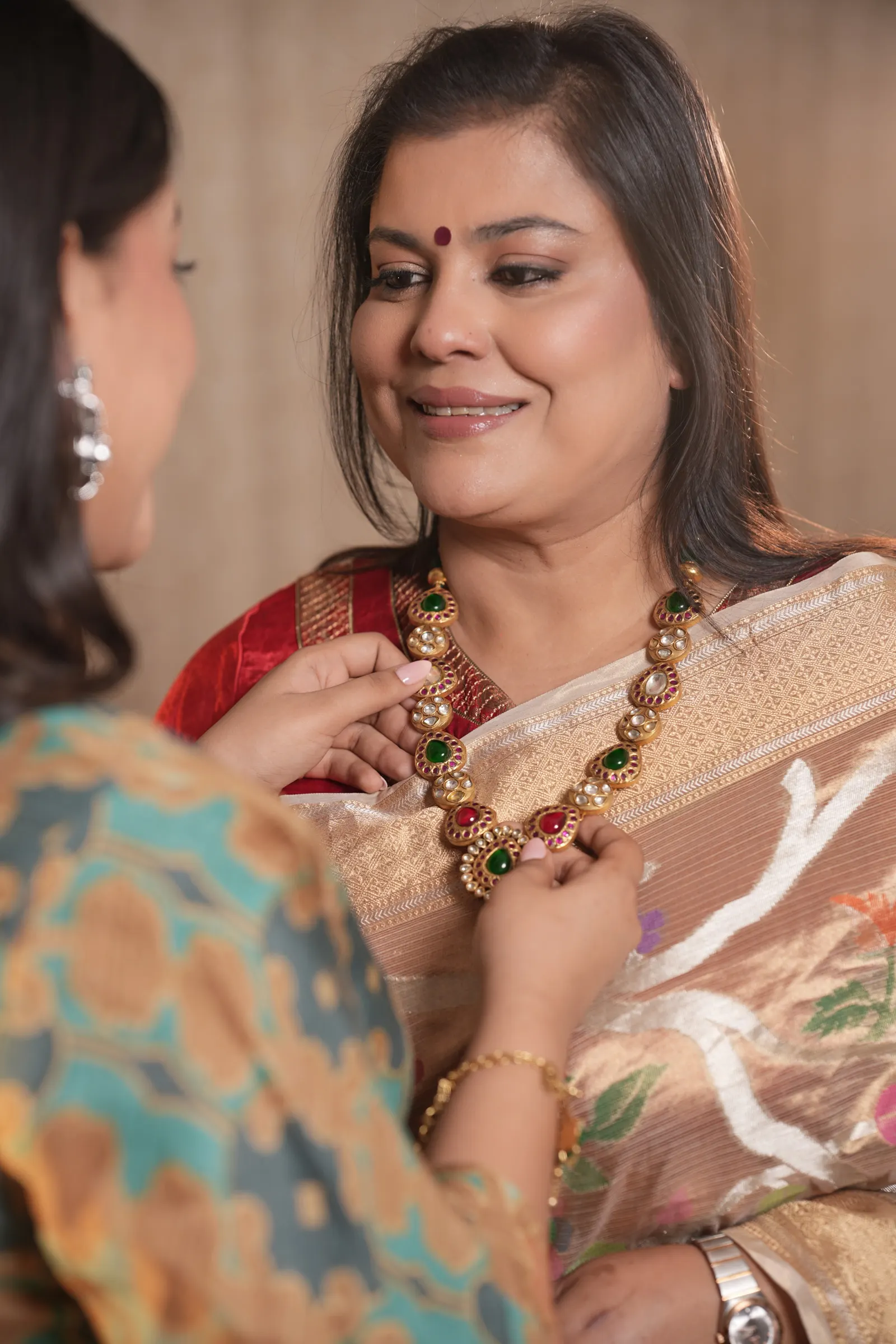 Mansi and Khushi, mother and daughter, adjusting a polki necklace together